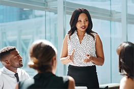 Female business student presenting to peers in conference room