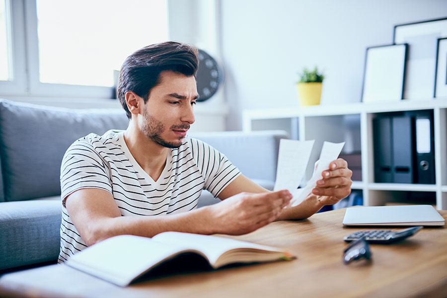 Image depicting a man at home going over receipts