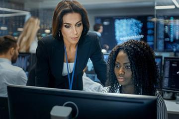 Professor instructing a student in front of a computer.