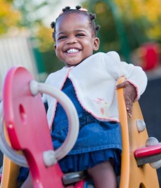 A happy girl smiles as she plays in a playground