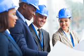 Three people at a construction site wearing blue protective helmets