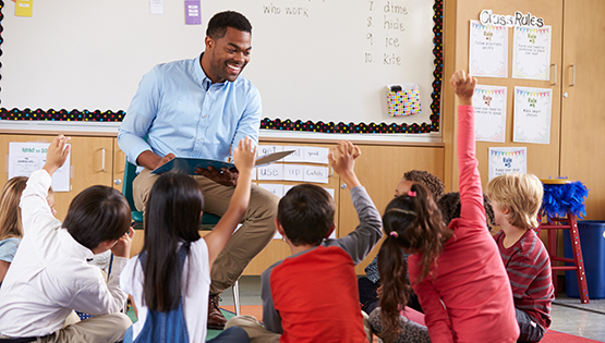 male teacher in classroom taking questions.